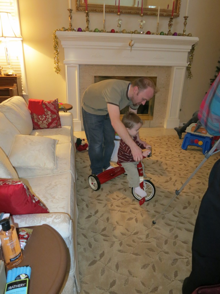 By Christmas evening, Emrick was feeling MUCH better, taking notice of his presents for the first time really. Here's Marcus helping him get acquainted with the trike.