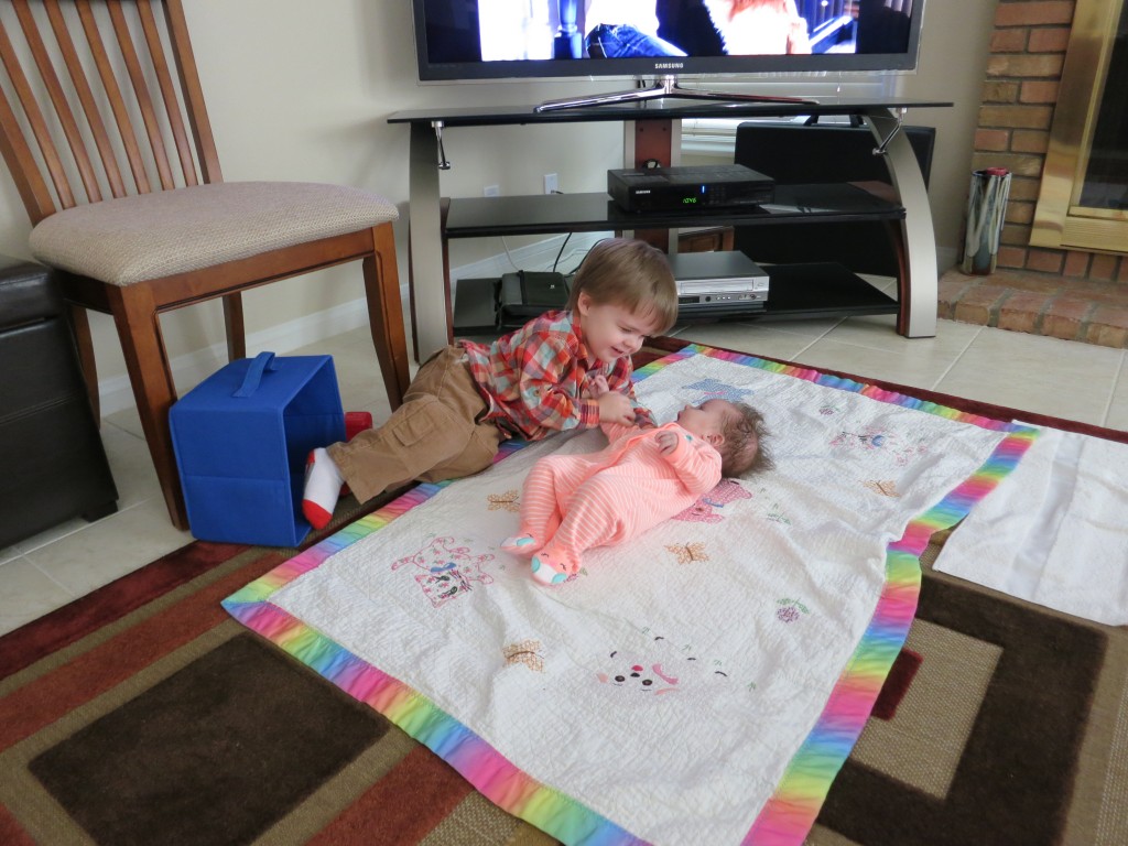 Once again, Emrick gets close to Holly while she lies on the floor. That's Mommy's old baby blanket that she's lying on -- a blanket made for me by Grandma Betty and later restored for me by Cinda..